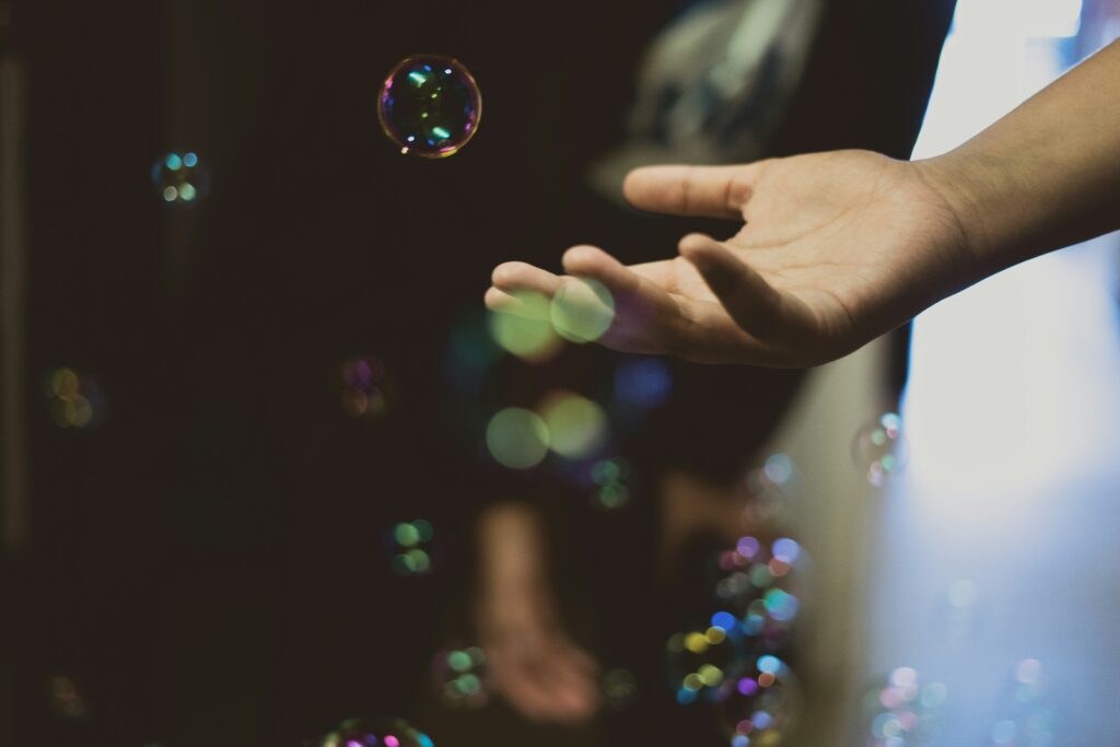 Hand reaching out for bubble in sunlight