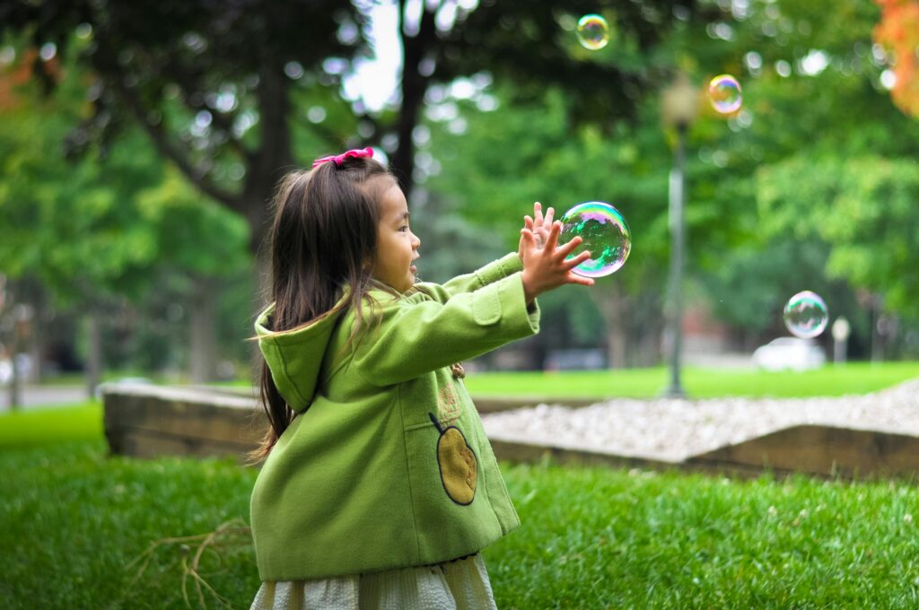 Chasing bubbles in a garden wearing green coat